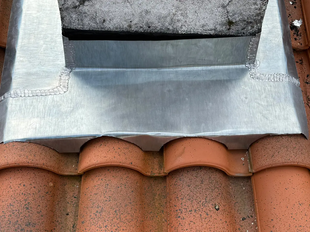 Zinguerie soudée sur mesure au pied d'une cheminée